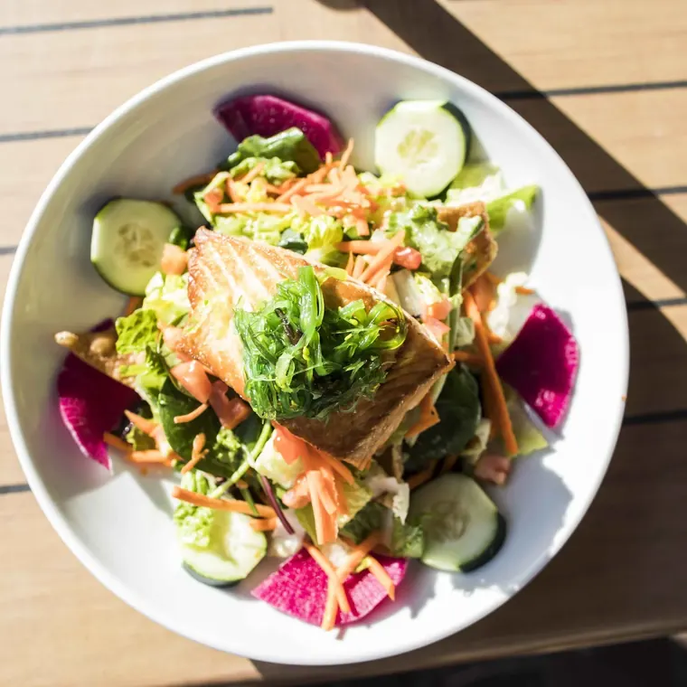 A salad with greens, avocado and radish
