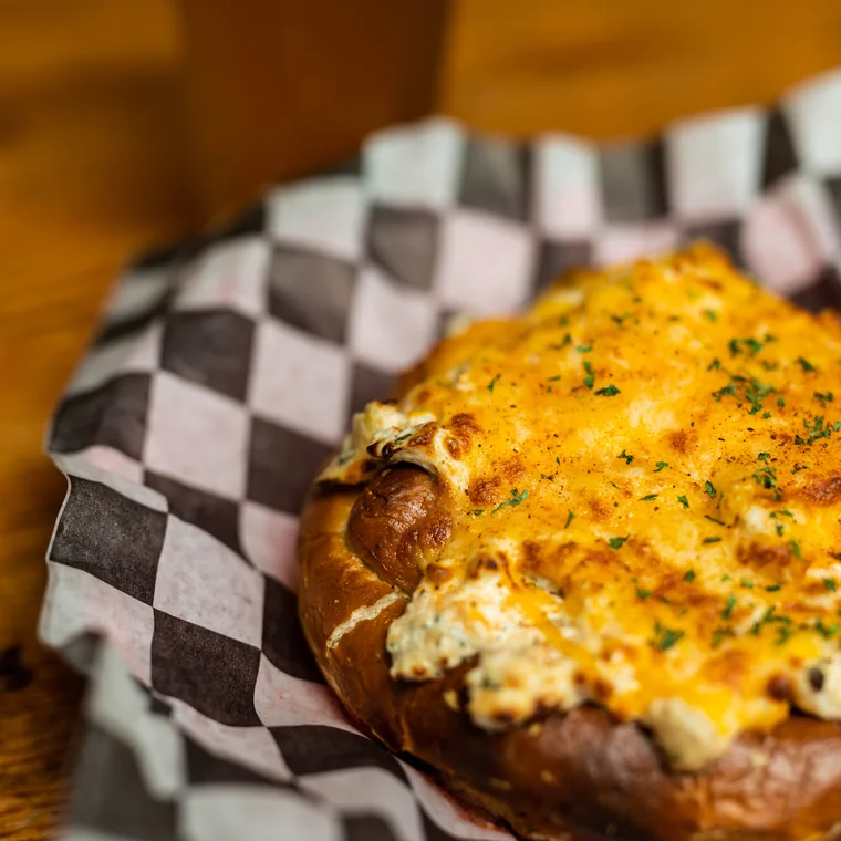 The crab pretzel, a jumbo pretzel topped with crab dip and baked cheese, served with a beer